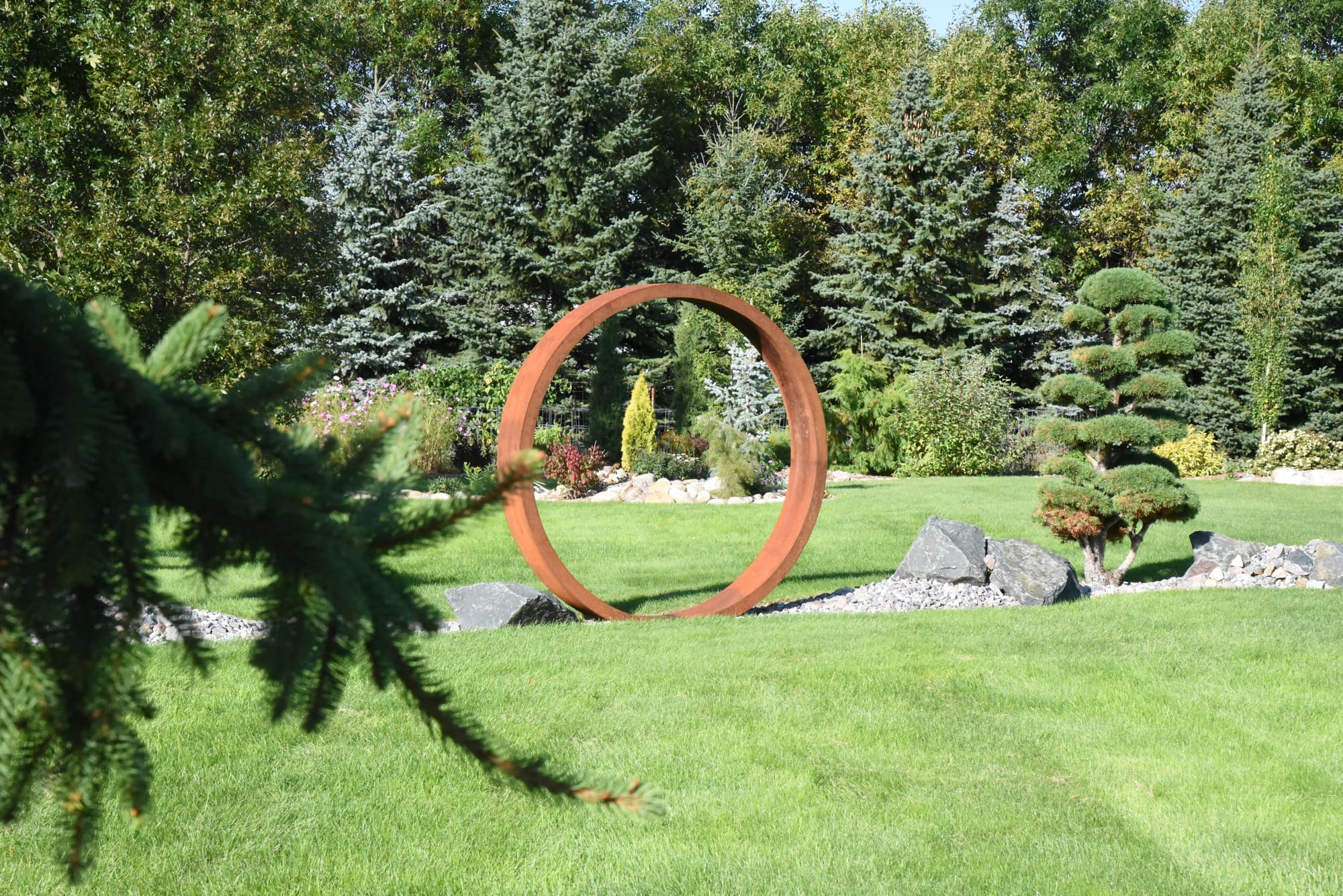 A Narrow Landscape Bed Including Metal Garden Art and Unique Plants