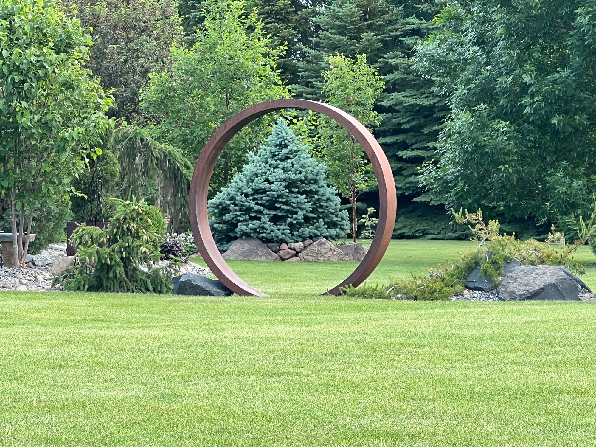 A Narrow Landscape Bed Including Metal Garden Art and Unique Plants