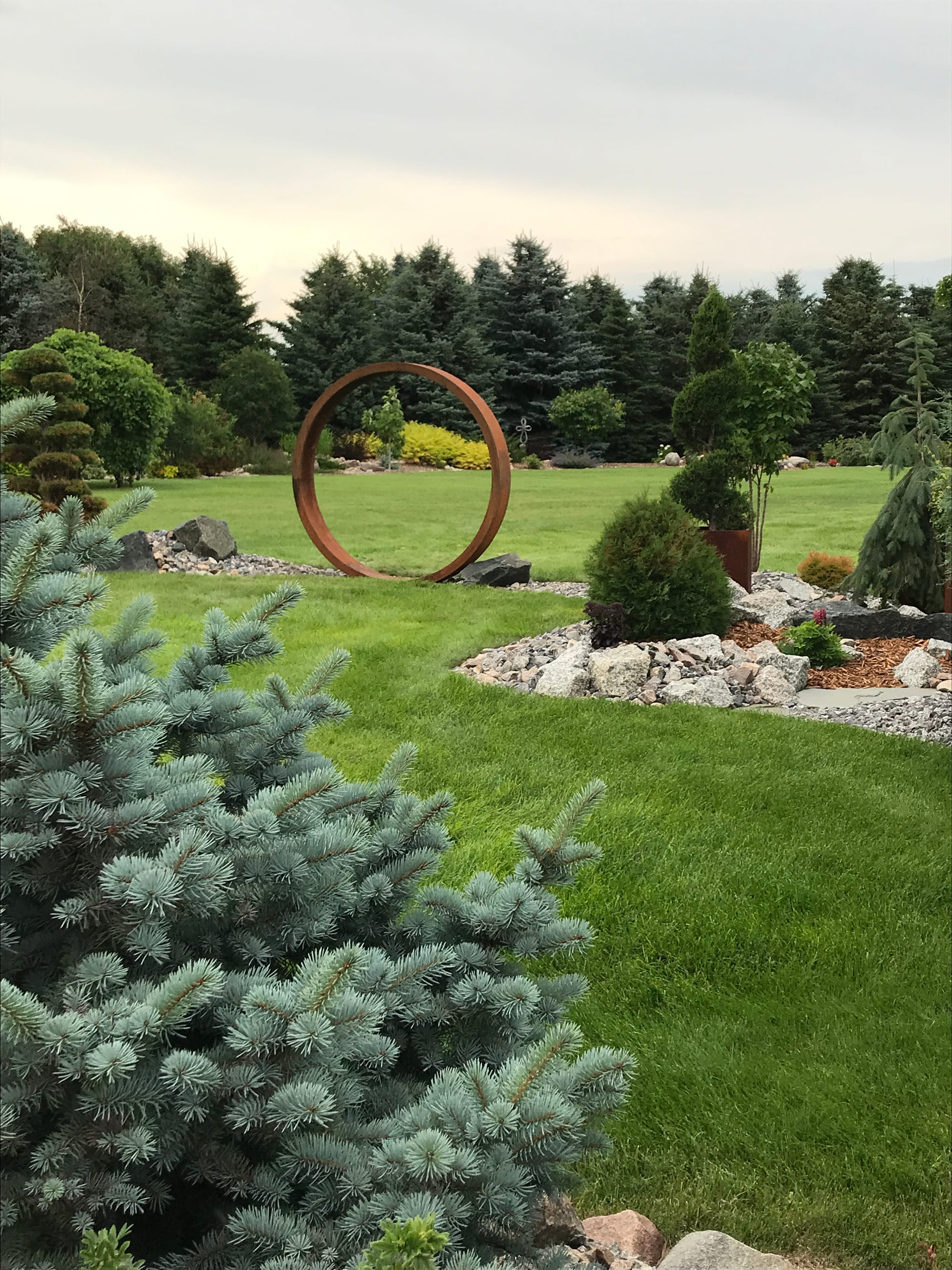 A Narrow Landscape Bed Including Metal Garden Art and Unique Plants