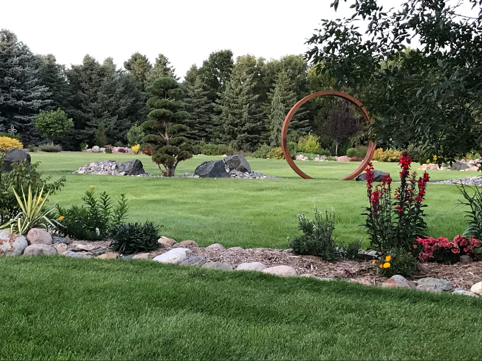 A Narrow Landscape Bed Including Metal Garden Art and Unique Plants
