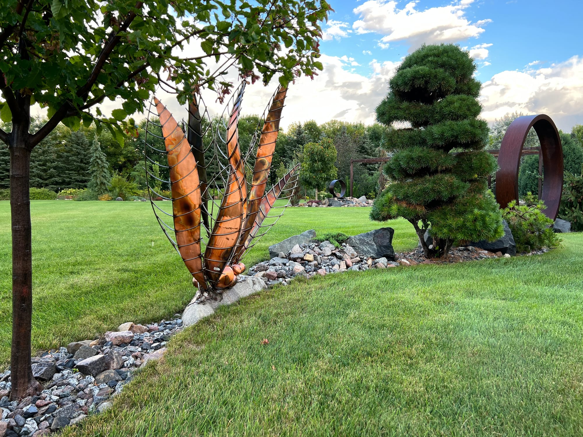 A Narrow Landscape Bed Including Metal Garden Art and Unique Plants